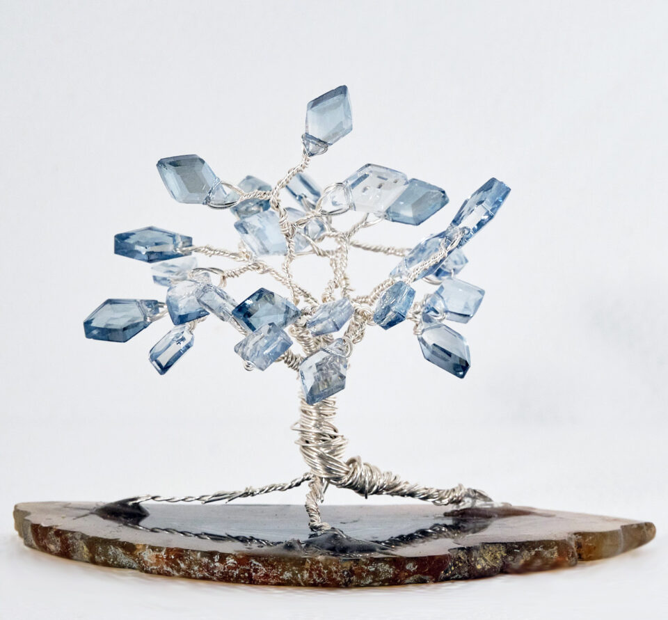2.5" wired tree with silver colored wire and kite shaped clear light blue glass beads on a slice of earth tone agate